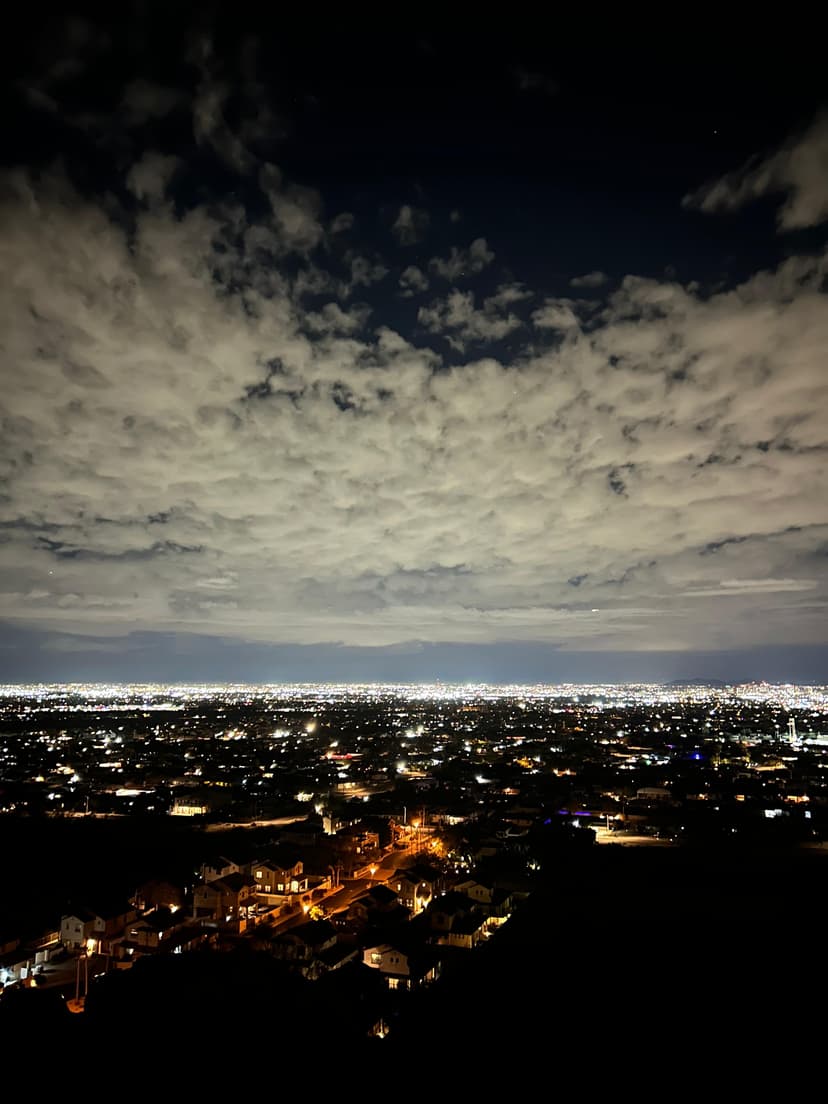City lights glowing under thick evening clouds