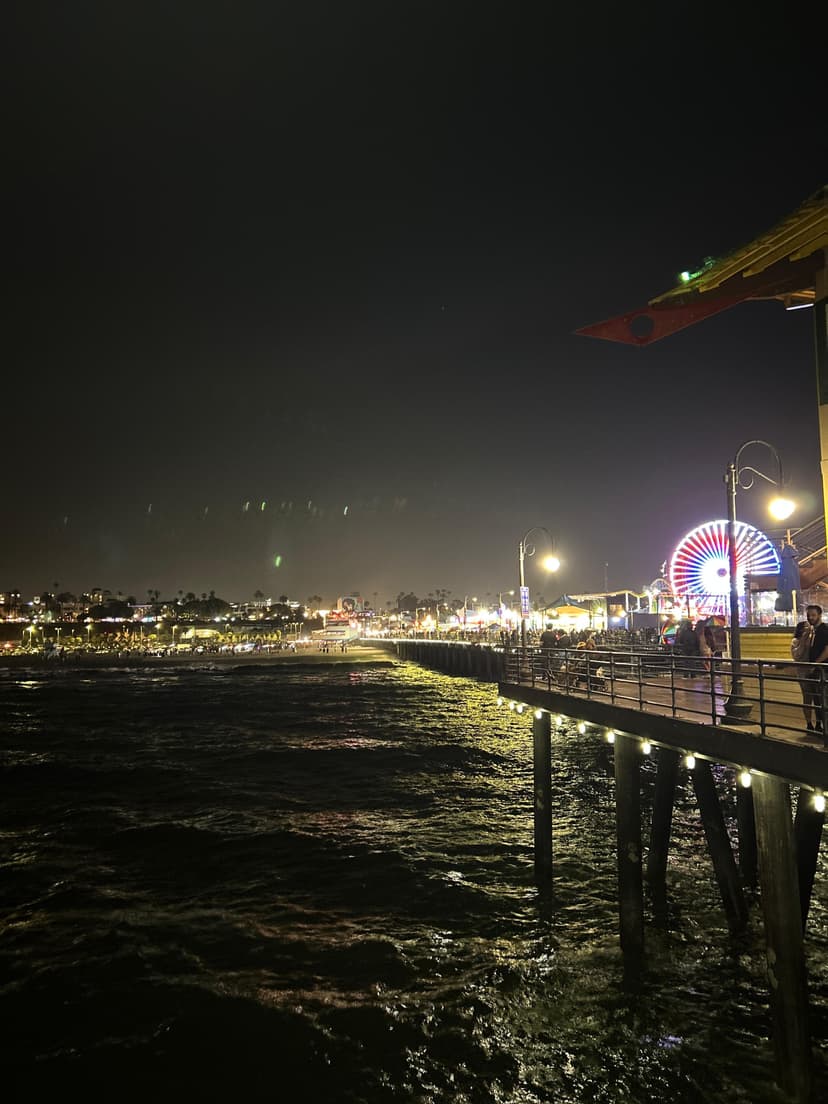 Santa Monica Pier at night with ocean waves and glowing ferris wheel