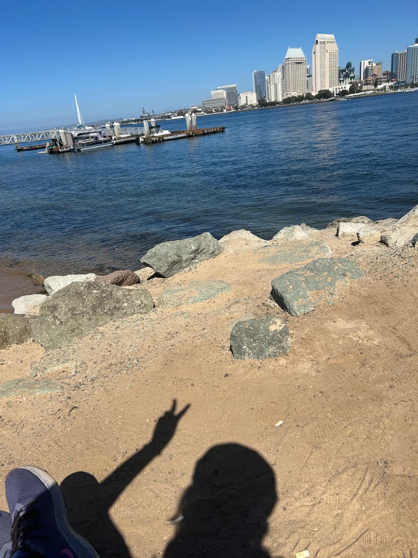 Peace sign shadow by the beach with San Diego skyline across the bay