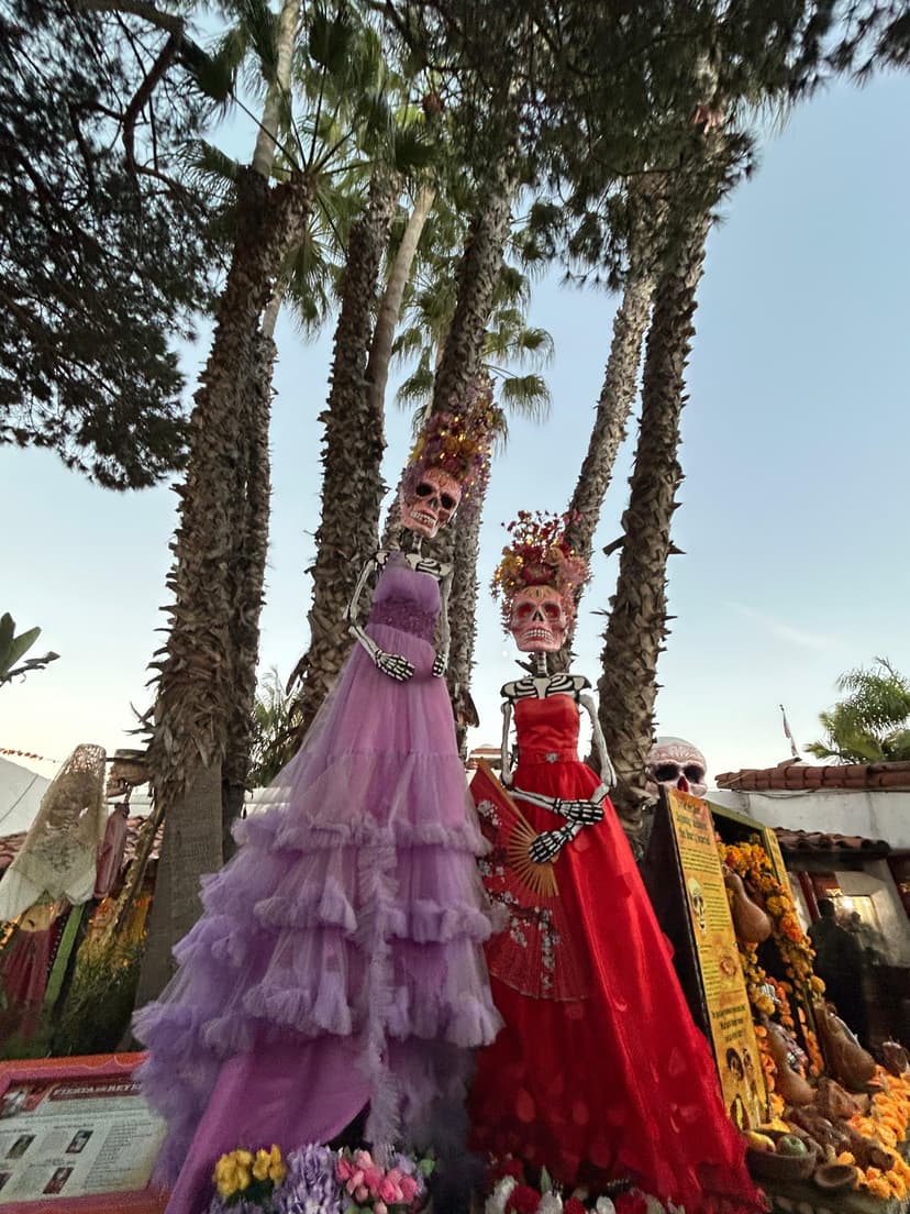 Tall skeleton figures in colorful dresses for Día de los Muertos celebration