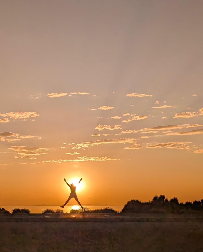 Person jumping in front of a golden sunset at Antelope Island