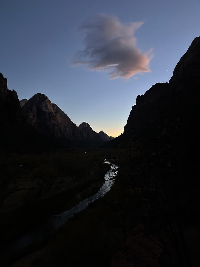 Zion canyon at dusk with a glowing river and silhouette mountains