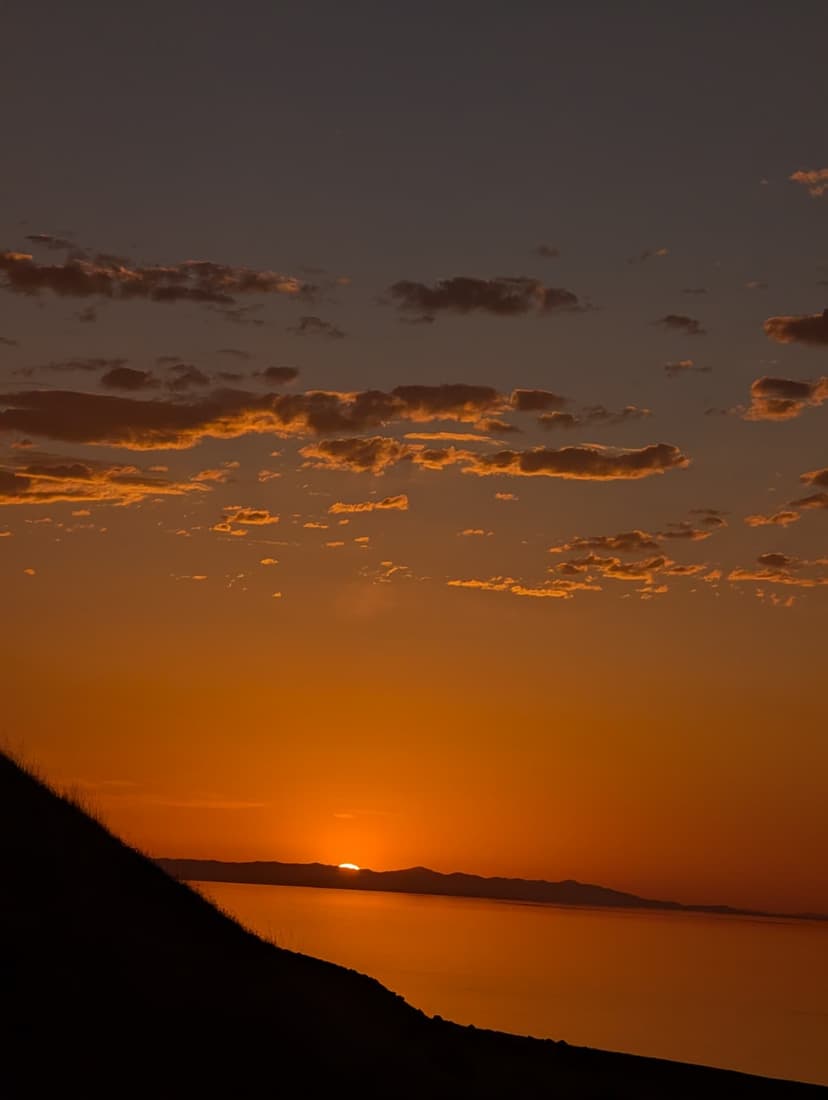 Sun setting behind the mountains, sky painted in deep orange hues