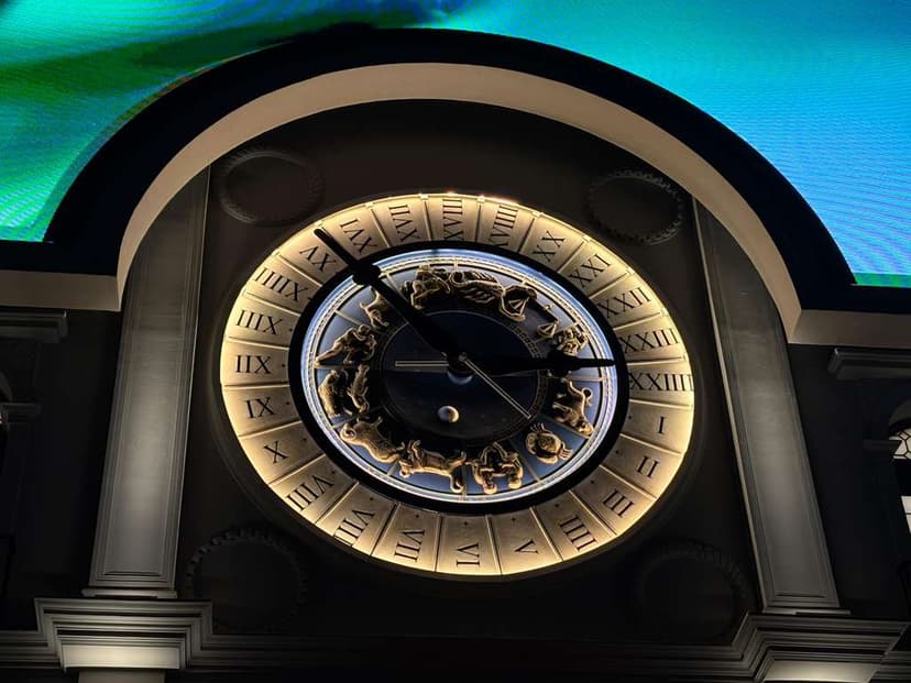 Close-up of ornate clock with Roman numerals and zodiac carvings