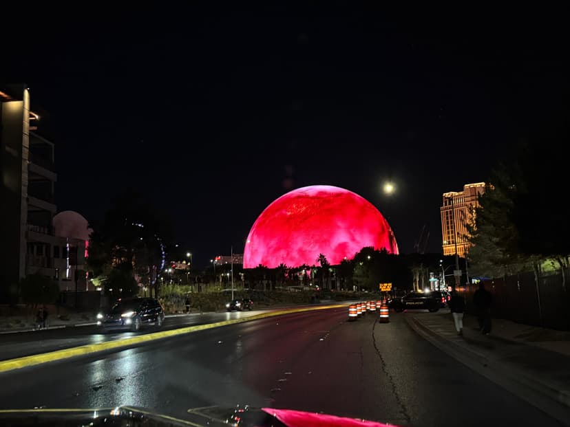 Red illuminated Las Vegas Sphere seen from the road at night