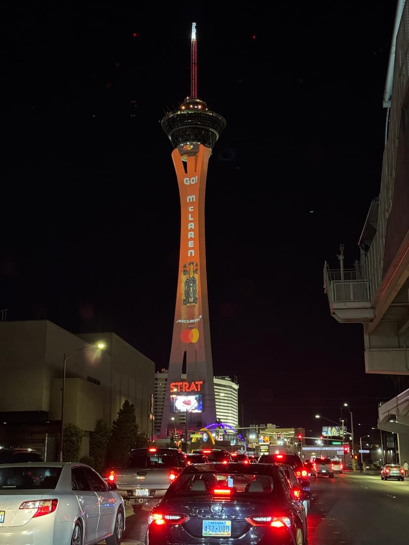 STRAT Tower lit in orange with McLaren projection and city traffic below