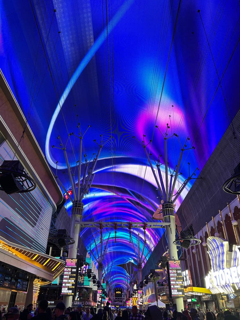 Crowded Fremont Street canopy glowing in blue and purple neon lights