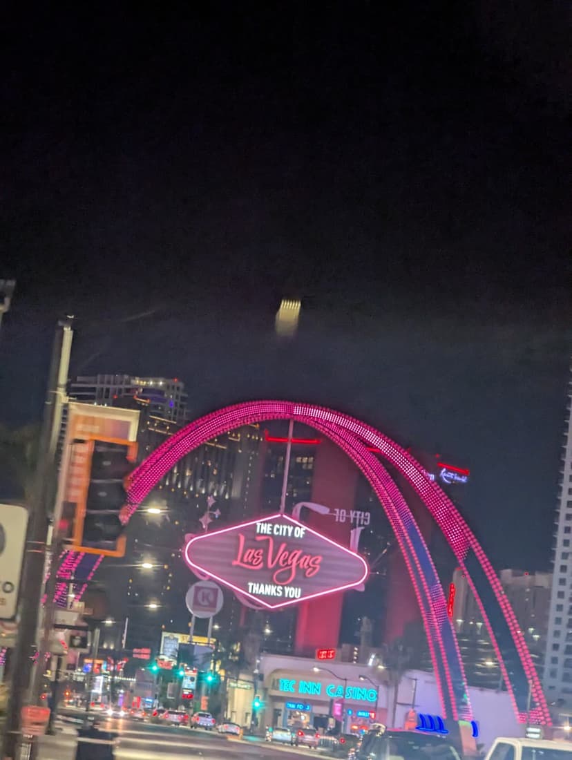 The iconic 'City of Las Vegas' sign lit in pink neon under night sky