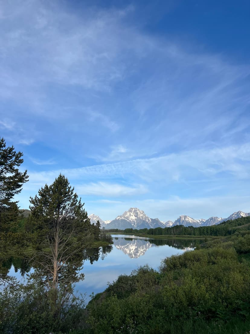 Grand Teton mountain range reflected perfectly in calm blue waters on a clear day