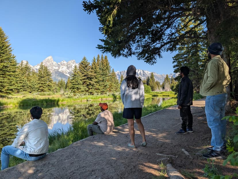 Group of people admiring the reflection of the Teton mountains by a tranquil river