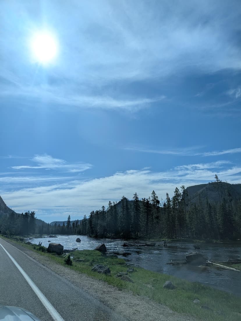 Sunny highway running beside a flowing river under a bright blue Wyoming sky